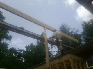 Carpenter setting a ridge beam over a new addition frame — Ice Dam Removal by Roofing Brothers in Millville